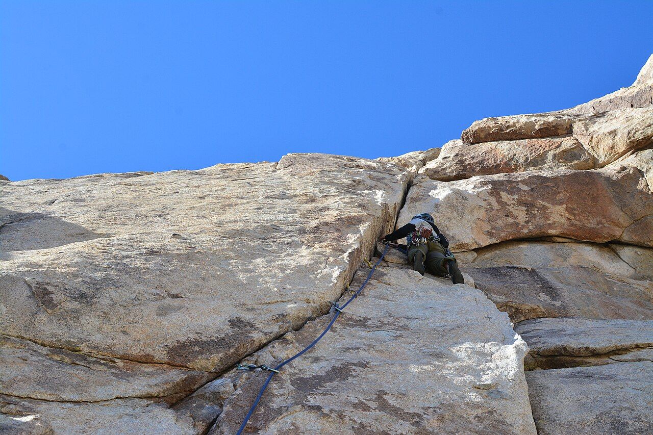 Climber leading a granite crack route with rope and gear
