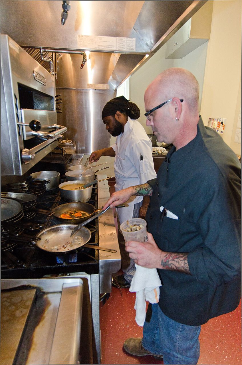 Chef and line cook preparing dishes at a busy kitchen line